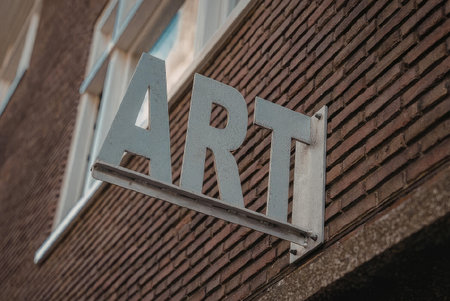 A close-up photograph of a metal sign reading 'ART' mounted on a brick wall.