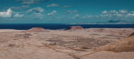 A panoramic view of a desert landscape with a body of water in the background and a blue sky with...