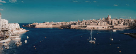 A serene harbor scene with boats floating on calm waters, surrounded by buildings and a clear blue...