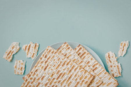 A white plate filled with crackers and some crackers scattered around it on a light blue surface
