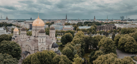 An aerial view of a city with a large building featuring a golden dome, surrounded by trees and...