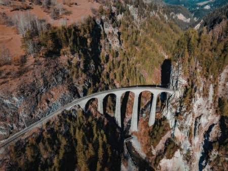 An aerial view of a bridge with multiple arches spanning across a valley surrounded by mountains and...