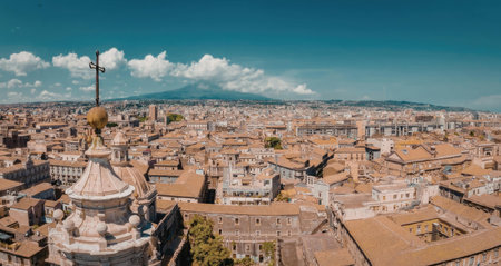 An aerial view of a city with orange roofs and a large cross on top of a building, set against a...