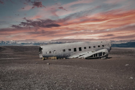 The image depicts the wreckage of a plane lying abandoned on a barren, rocky landscape under a...