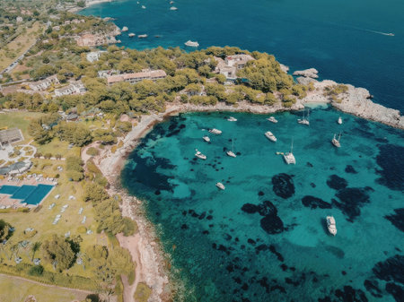 An aerial view of a coastal town with a beach, boats in the water, and a pool and buildings on the left side.の写真素材