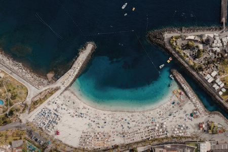An aerial view of a crowded beach with a large body of water and a pierの写真素材