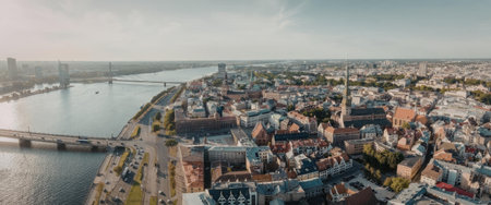 An aerial view of a city situated by a river, showcasing a mix of buildings and a bridge connecting the city to another landmass.の写真素材