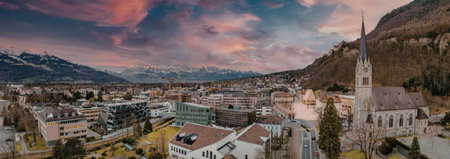 A panoramic view of a small town nestled in a valley with a church steeple and buildings under a...