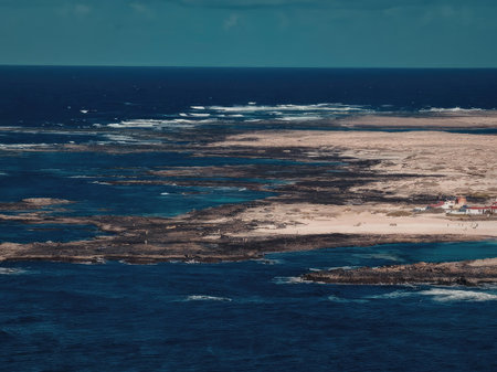 An aerial view of a coastline showing signs of erosion with patches of sand and seaweed visible in...