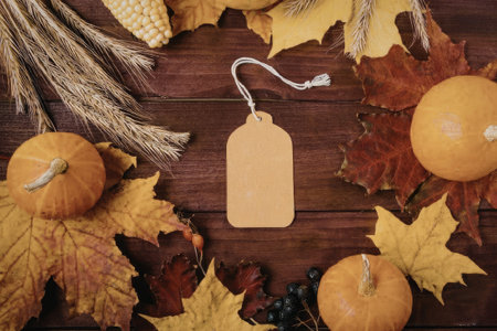 A collection of autumnal items including pumpkins, leaves, and grains arranged on a wooden table...
