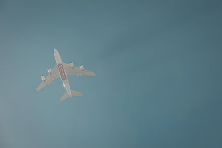 An airplane flying high in a clear blue sky, showcasing its sleek design and vibrant colors.の写真素材