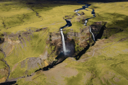 An aerial view of a waterfall and river flowing through a green landscapeの写真素材