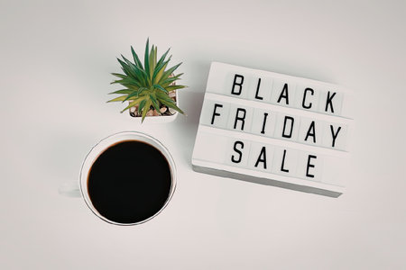 A promotional image for Black Friday sales featuring a cup of coffee, a small plant, and a sign with...
