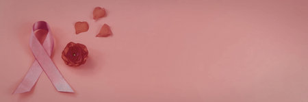 A pink ribbon, a pink rose, and heart shapes on a pink background