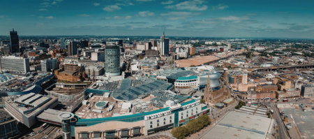 A panoramic view of a modern city with various buildings and skyscrapers under a clear blue sky.