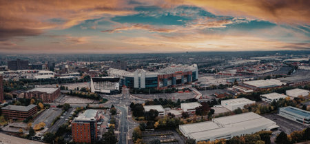 Aerial view of a city during sunset, showcasing buildings and trees under a vibrant sky