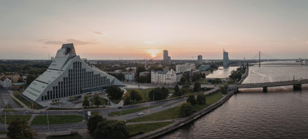 Aerial view of a city at sunset, featuring modern glass buildings and a bridge over a body of water.の写真素材
