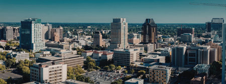 A panoramic view of a city's downtown area with tall buildings and skyscrapers under a clear blue sky.