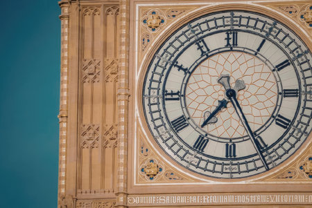 A close-up view of a large clock face with Roman numerals and ornate gold details against a blue...