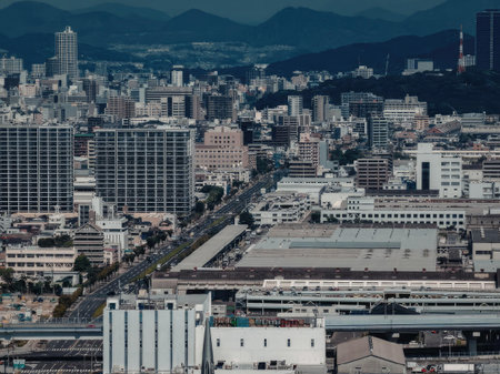 Aerial view of a city with a mountain range in the background. The city has many buildings and...