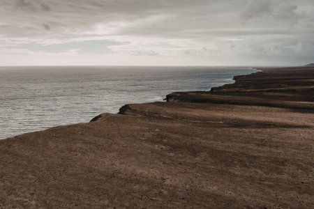 A rocky coastline on a cloudy day with the sea to the left and rugged terrain to the rightの写真素材