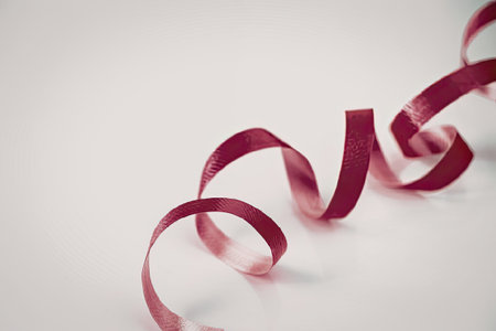 A pink ribbon is curled and placed on a white surface, creating a visually appealing contrast.