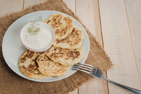 Delicious potato pancakes served with sour cream on a rustic table
