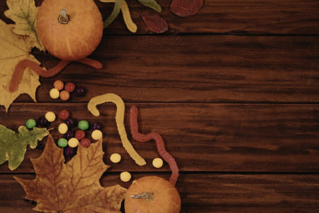 The image depicts a wooden table with fall season decorations including pumpkins, leaves, and candy.