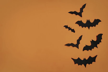Flying bats silhouette against orange background