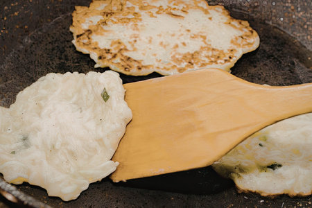 A close-up shot of food being cooked in a pan with a wooden spatula