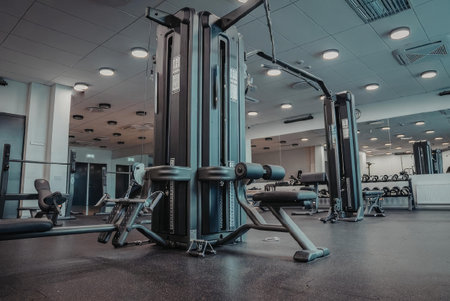 A gym interior featuring a multi-functional workout machine, free weights, and other exercise...