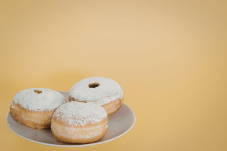 Delicious donuts on a plate against yellow background
