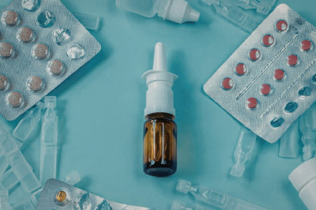 The image features a collection of medications and pills arranged on a light blue surface. A dropper...