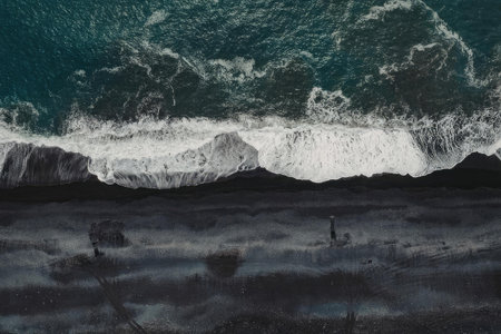 Aerial view of a wave crashing on the shore, showcasing the ocean's power and beauty.の写真素材