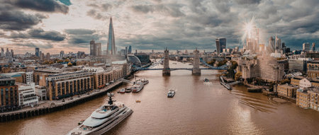 A panoramic view of London cityscape with a river and boats, showcasing the city's skyline and...