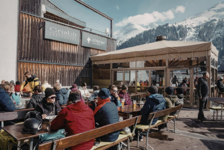 a group of people sitting at tables outside a cafe with a mountain range in the backgroundの写真素材