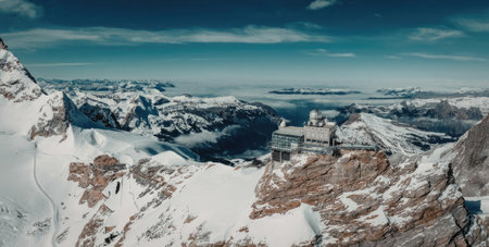 The image showcases a breathtaking panoramic view of snow-covered mountains with a building situated...