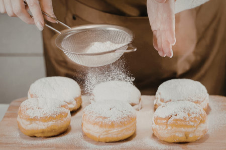 Powdered sugar sprinkled on delicious donuts by bakerの写真素材