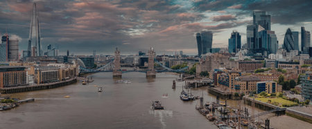 A panoramic view of the River Thames with boats and cityscape in the background during sunset.