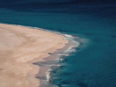 A tranquil beach scene featuring a sandy shore meeting turquoise ocean waters.