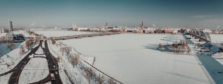 A snowy landscape with a road and cityscape in the background under a clear blue sky.