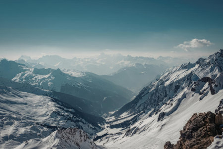 A breathtaking view of a snow-covered mountain range under a clear blue sky with a few clouds.