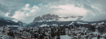 A panoramic view of a snow-covered village nestled in the mountains, with trees and buildings...