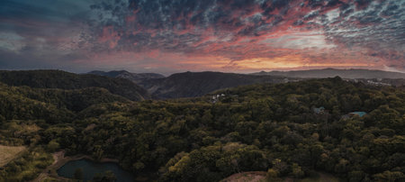 A serene landscape of mountains and trees under a vibrant sunset sky.