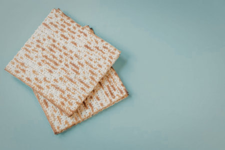 A stack of two matzo crackers on a light blue background, symbolizing Jewish tradition and Passover...