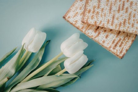 A bouquet of white tulips and two pieces of matzo on a light blue surfaceの写真素材