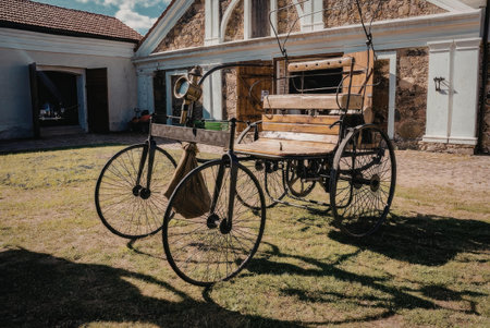 A vintage bicycle with a wooden cart attached, parked on a grassy area in front of a brick building.