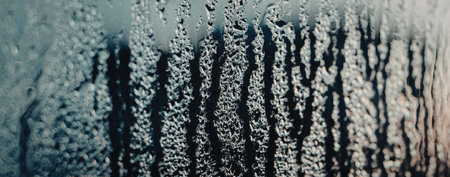 Close-up of water droplets on a window pane, creating a blurred view of the outside.