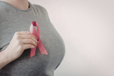 Woman holding pink ribbon for breast cancer awareness