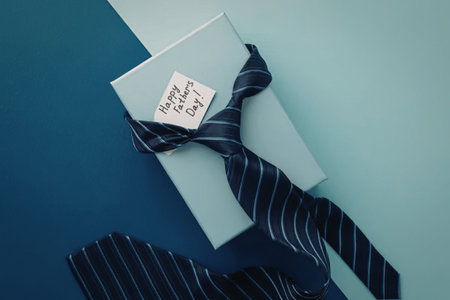 A light blue gift box wrapped with a navy blue tie with white stripes on a blue background